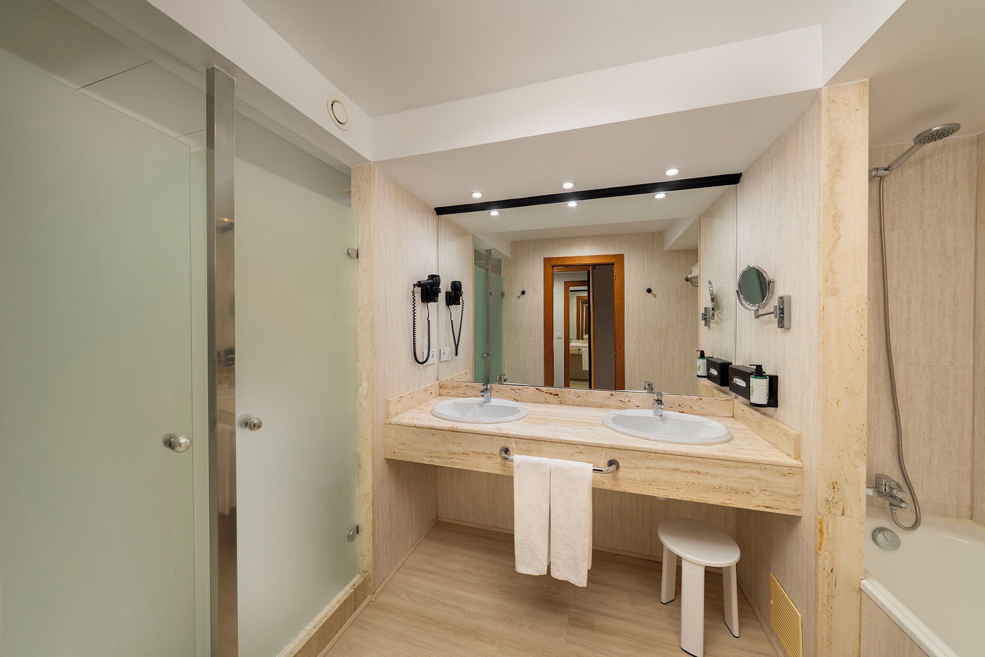 A modern bathroom with two sinks, a mirror, a towel rack, and a shower.