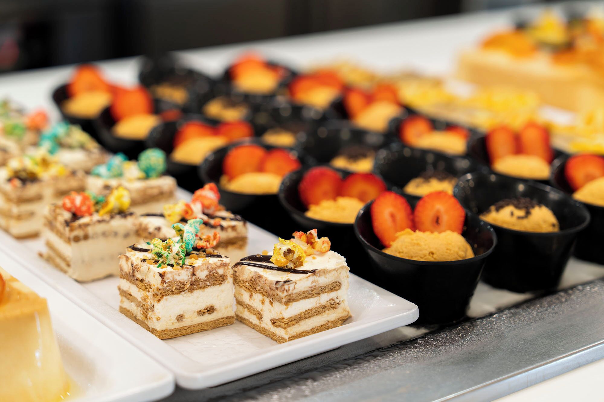 Eine Auswahl an Desserts auf einem Buffet, darunter Schichttorten und Obsttorten.