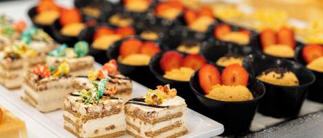 A variety of desserts on a buffet table, including layered cakes and fruit tarts.