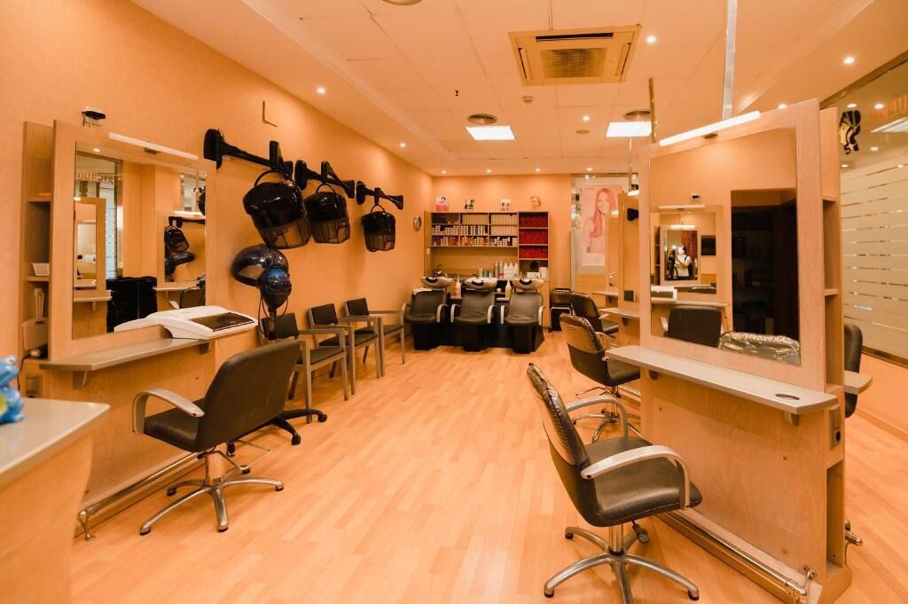 A salon with multiple chairs, mirrors, and shelves of hair products.