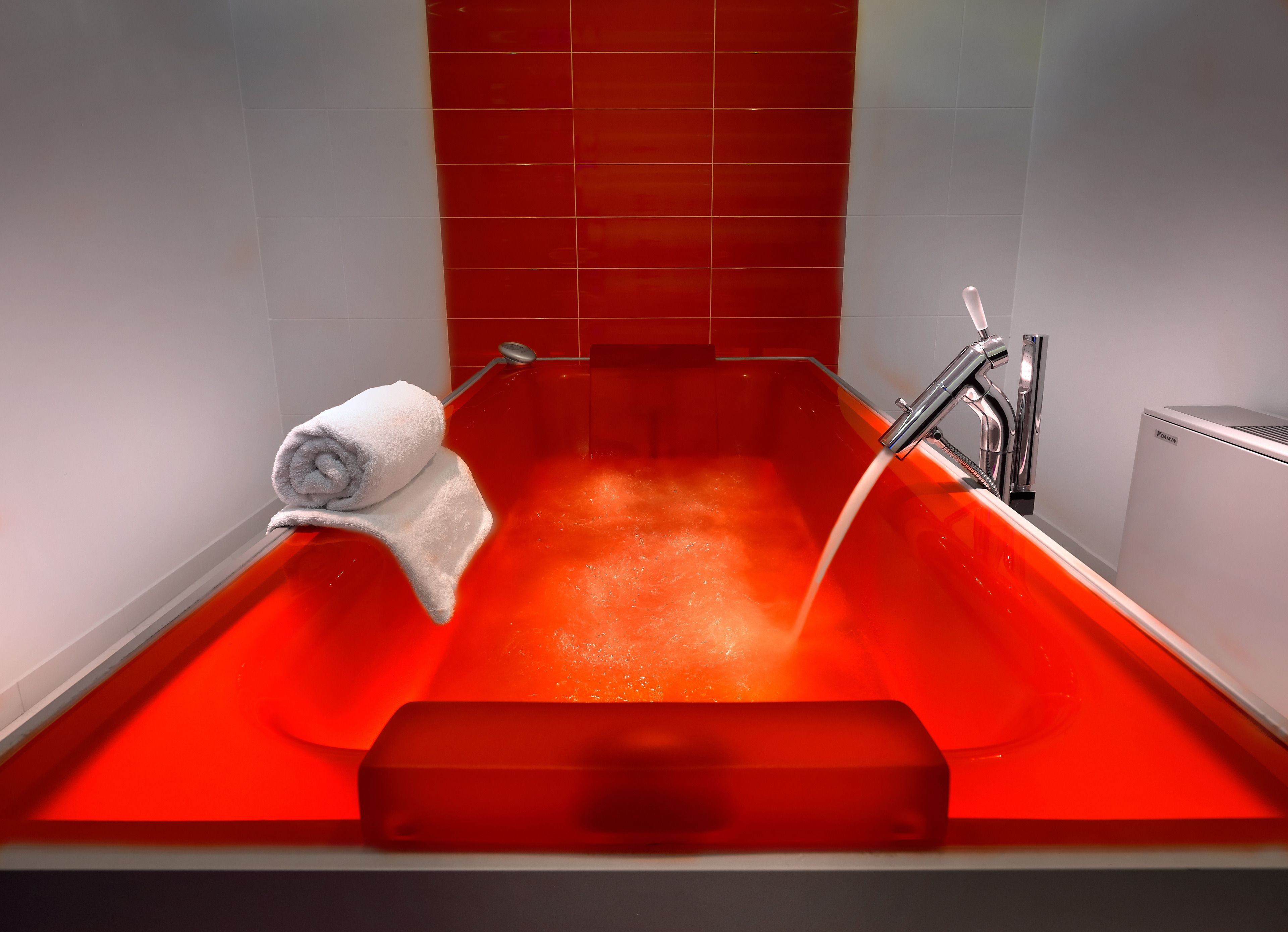 Eine Badewanne mit fließendem Wasser, ein Handtuch und ein Warmwasserbereiter.