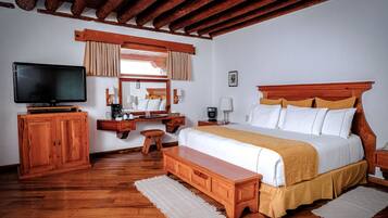 Un dormitorio con una cama de madera, televisión, escritorio y un banco.