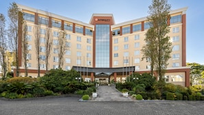 A multi-story hotel with a central glass entrance, surrounded by landscaped greenery and a paved driveway. - Intercity Caxias do Sul (Caxias do Sul)