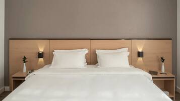 Una habitación de hotel moderna con una cama grande, dos mesitas de noche e iluminación en la pared.
