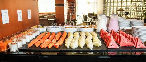 A buffet with various food items including sliced fruits, vegetables, and dairy products.