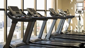 A row of treadmills in a gym with large windows and a TV screen on the wall. - Intercity Caxias do Sul (Caxias do Sul)