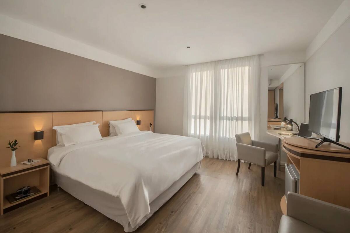 Une chambre d’hôtel moderne avec un grand lit, un bureau équipé d’un ordinateur, une chaise et un téléviseur.