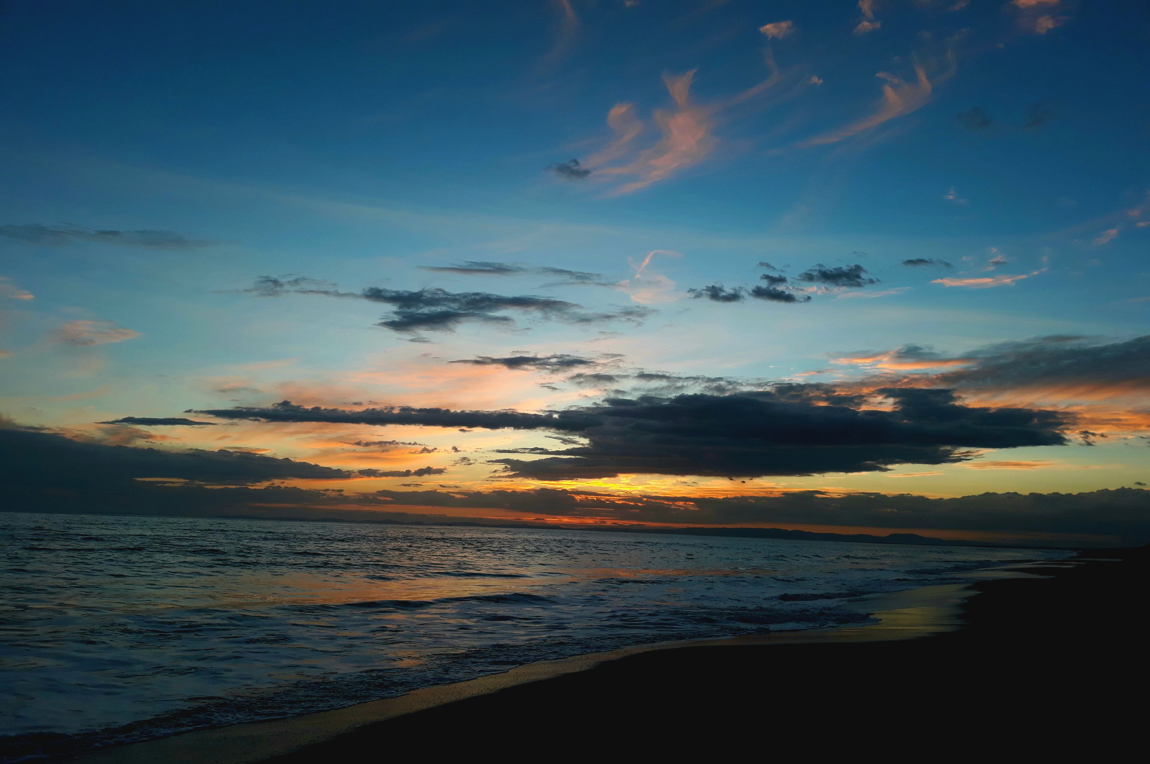 Une plage au coucher du soleil, avec une mer calme.