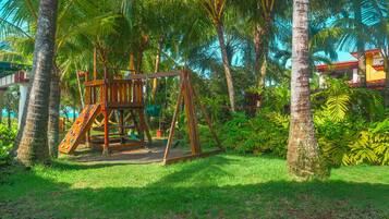 A wooden swing set surrounded by lush greenery and palm trees.