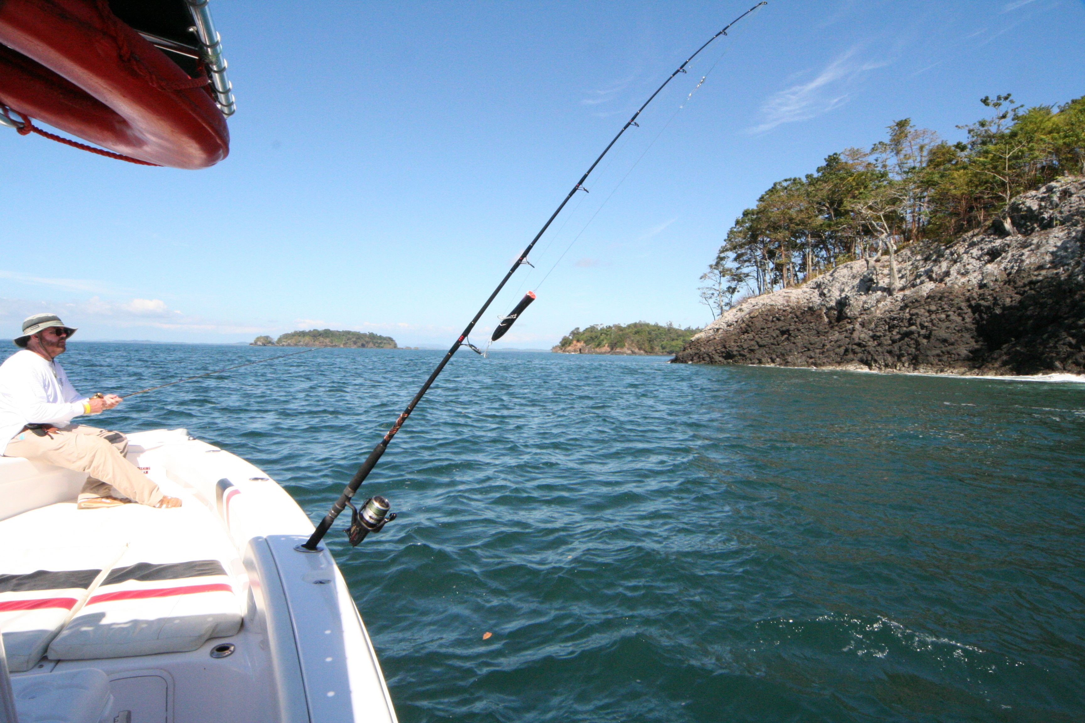 A boat with a fishing rod, a life preserver, and a person fishing.