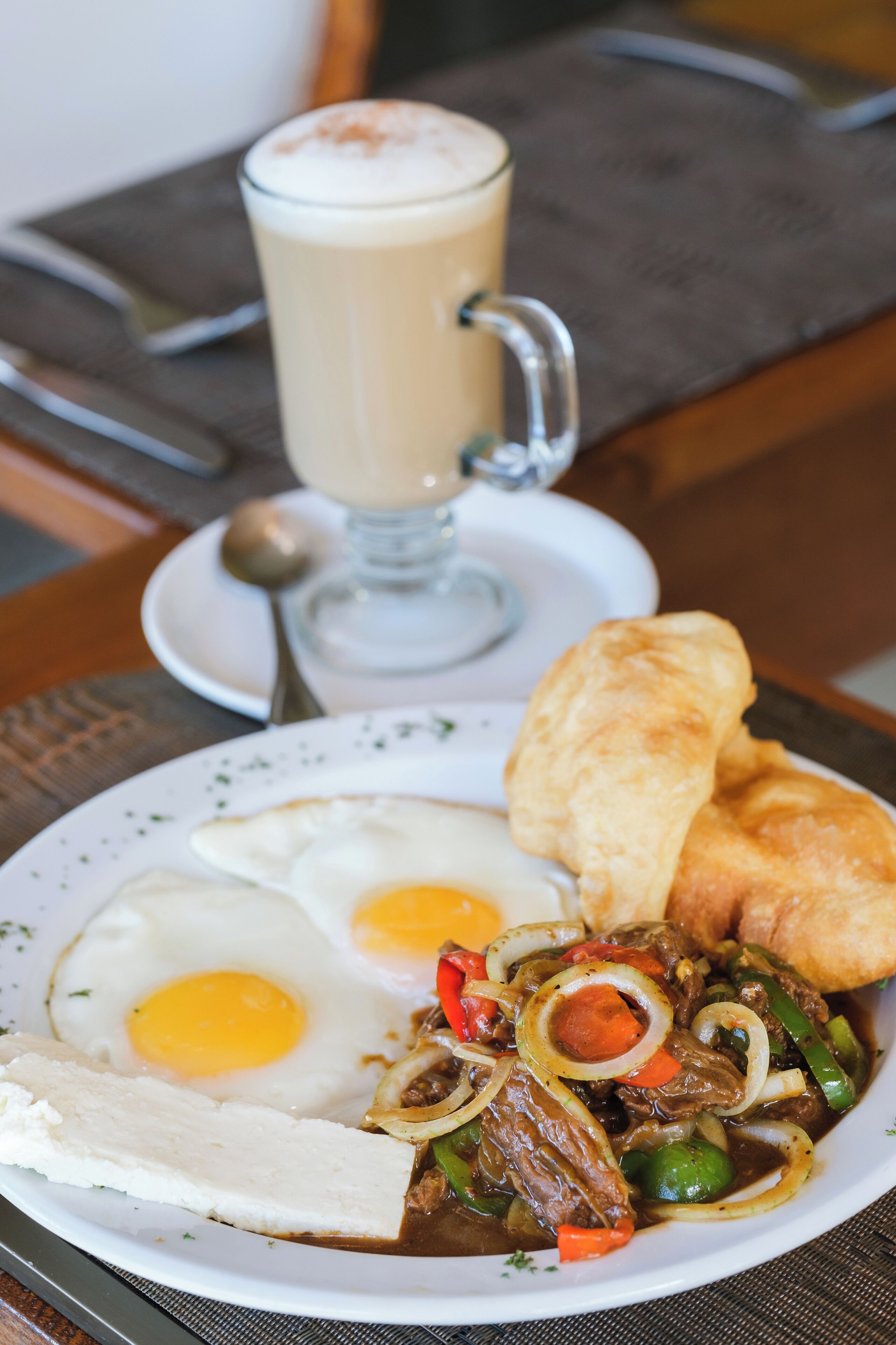 Une assiette de petit-déjeuner avec des œufs, des saucisses et des légumes, et une tasse de café sur une table.