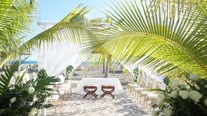 A beach wedding setup with a white canopy, chairs, and a table. - Las Olas Resort (Guarumal)