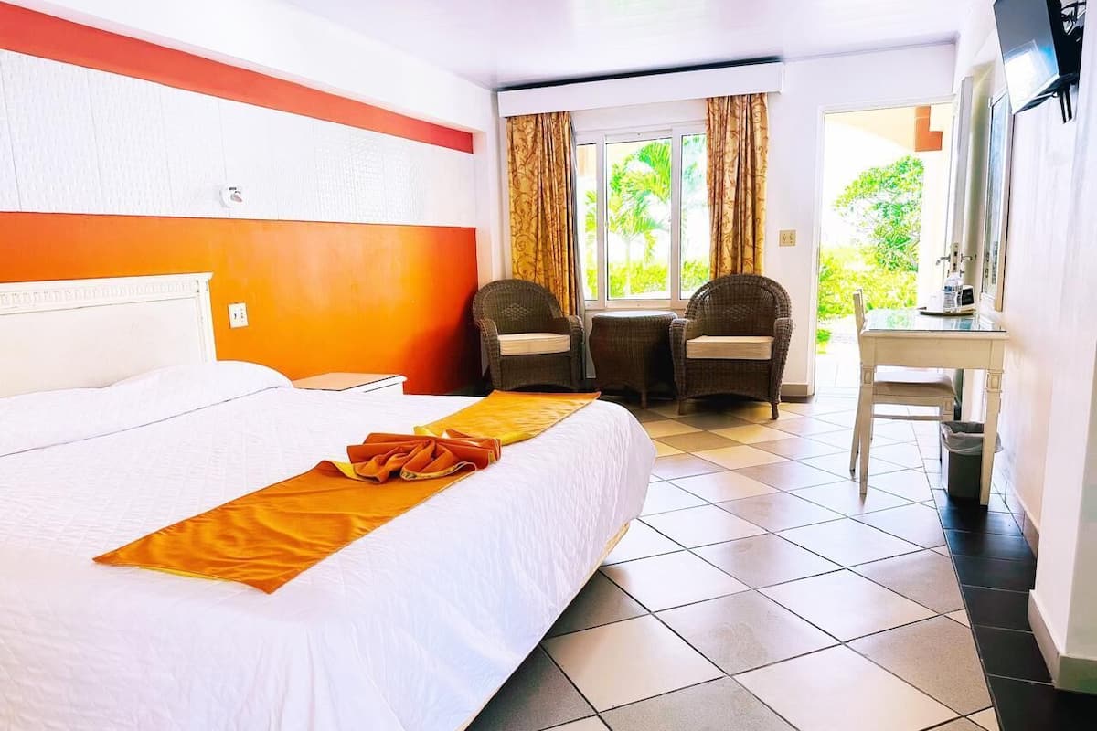 A hotel room with a large bed, two chairs, a small table, and a TV.