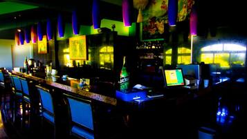 A bar area with a counter, chairs, and a bottle of Heineken.