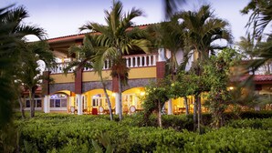 A hotel with a courtyard, palm trees, and a dining area with tables and chairs. - Las Olas Resort (Guarumal)