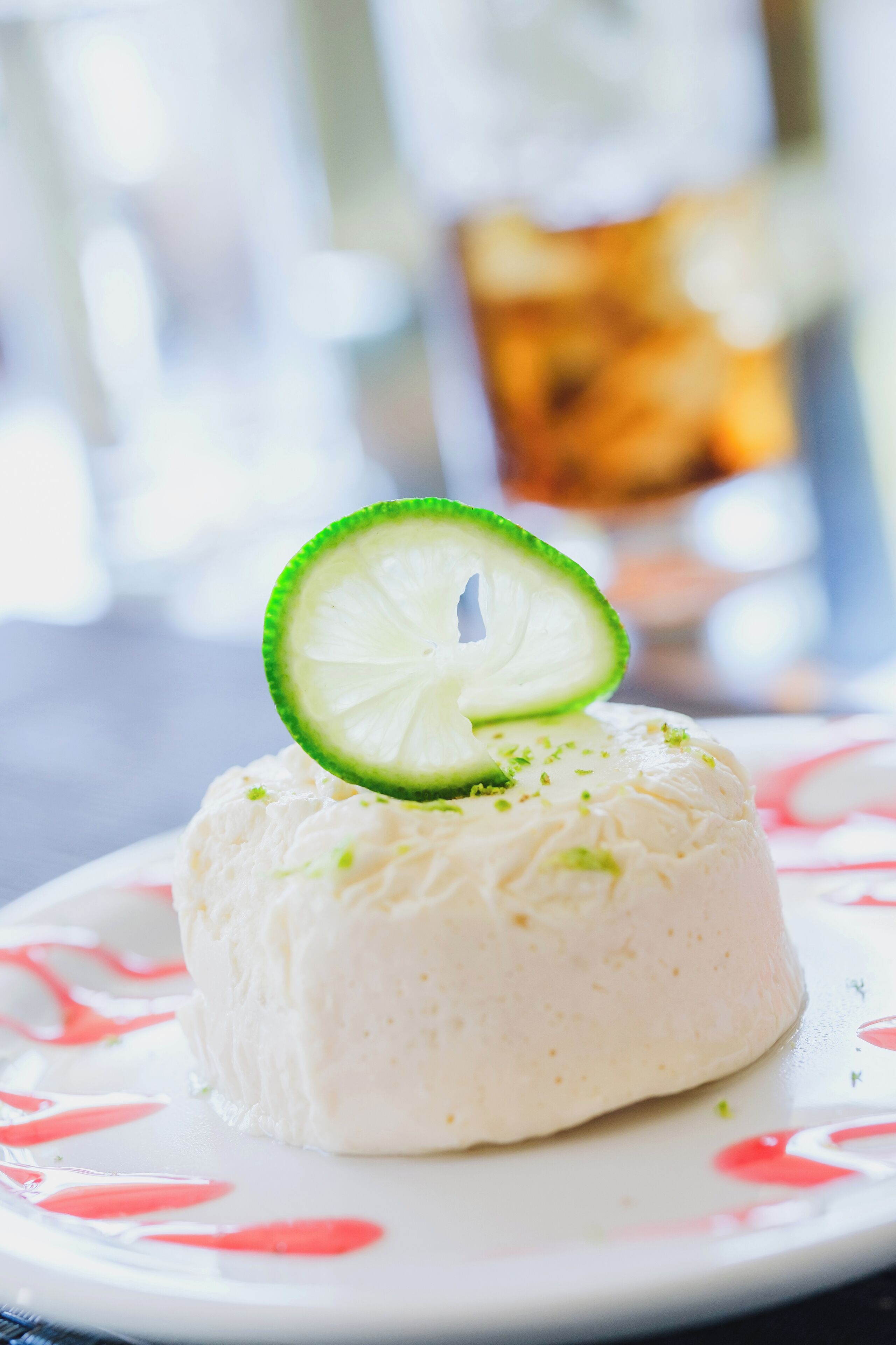 A dessert with a lime slice on top, served on a plate with a floral pattern.