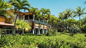 A multi-story hotel with a balcony, surrounded by lush greenery and palm trees. - Las Olas Resort (Guarumal)