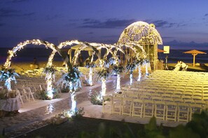 An outdoor wedding setup with rows of chairs, floral decorations, and a canopy structure. - Las Olas Resort (Guarumal)