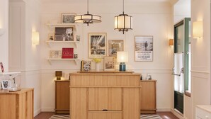 Een hotel lobby met een houten receptiebalie, hanglampen en ingelijste foto’s aan de muren.