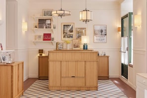 Eine Hotelhalle mit einem Holzbuchttisch, Pendelleuchten und gerahmten Fotografien an den Wänden.