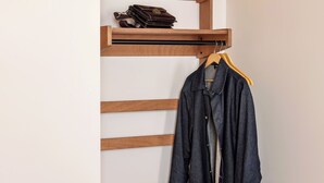 Een houten bank met een plank erboven, een opknop hangende jas en een opgevouwen handdoek.