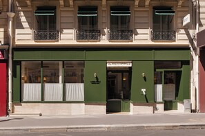 A building with a green facade, a sign reading 'ALFRED HOTELS,' and a door with a window.