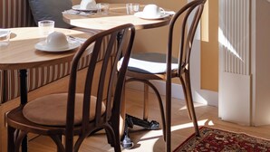 Een eetgedeelte met een houten tafel, stoelen en een witte open haard.