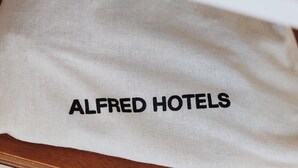Ein weißes Tuch mit dem Aufdruck "ALFRED HOTELS", platziert auf einer Holzfläche.