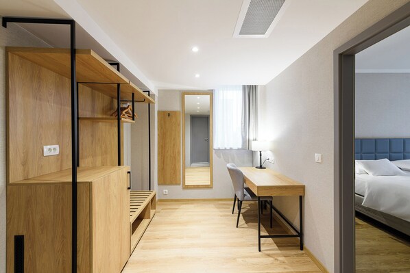 Una habitación de hotel con un escritorio de madera, una silla, una cama y un espejo.