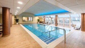 Una piscina interior moderna con vistas despejadas del horizonte de la ciudad a través de amplios ventanales.