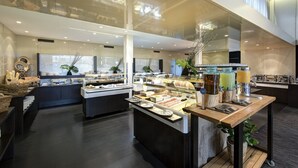 Un vestíbulo moderno de hotel con zona de buffet, vitrinas de cristal y un amplio ventanal con cortinas.