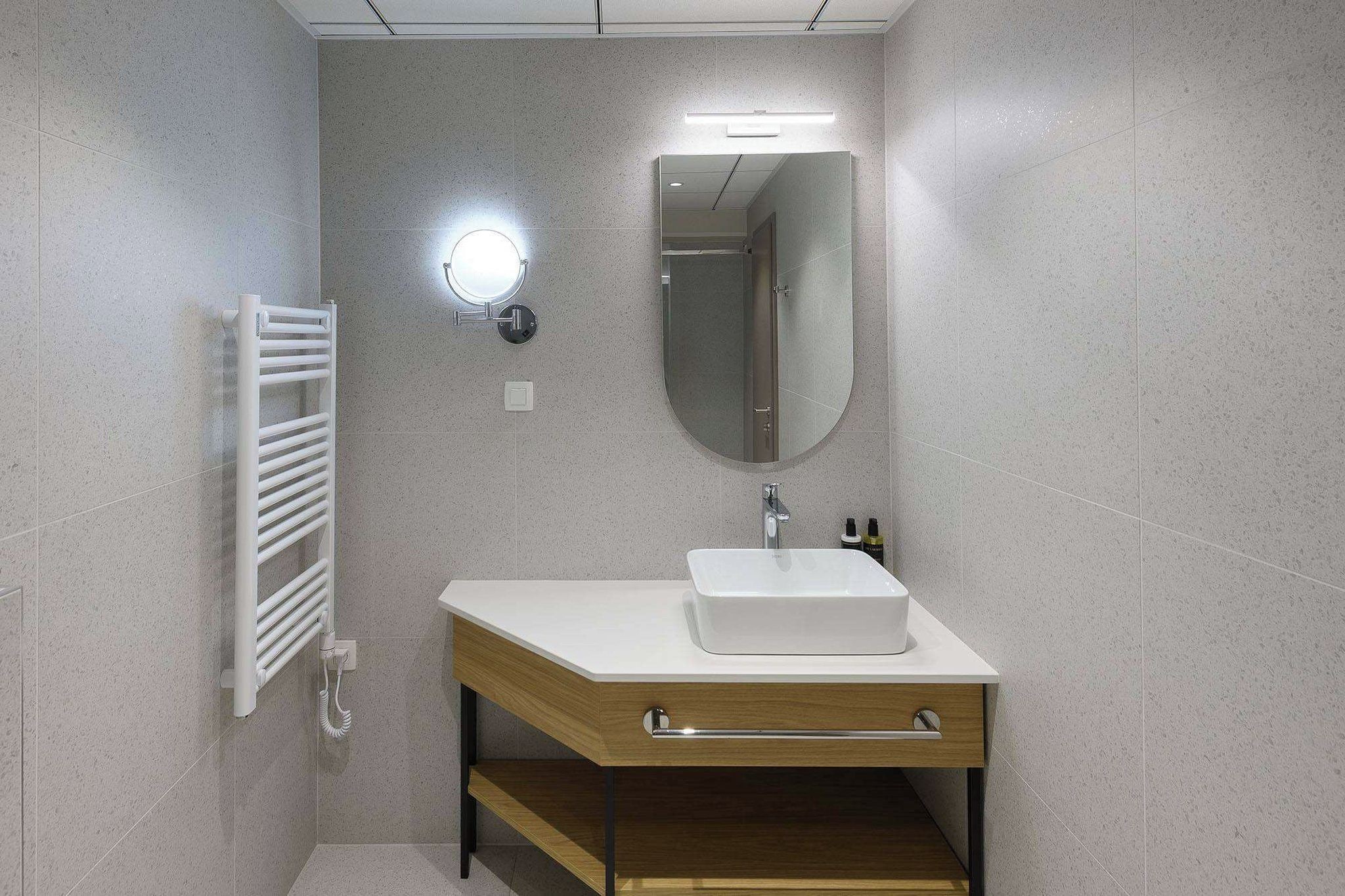 Casa de banho com lavatório branco, espelho e porta-toalhas.