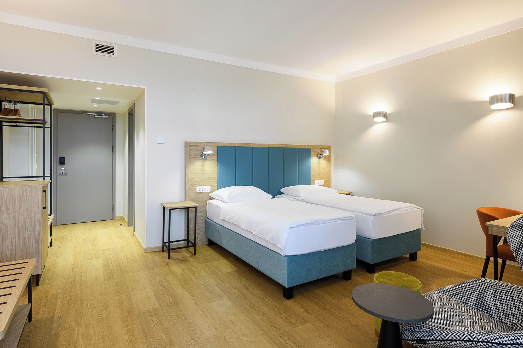 A hotel room with a double bed, bedside tables, a small desk, and a chair.
