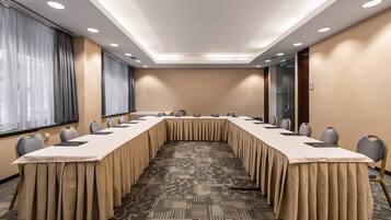 A conference room with a long table, chairs, and a patterned carpet.