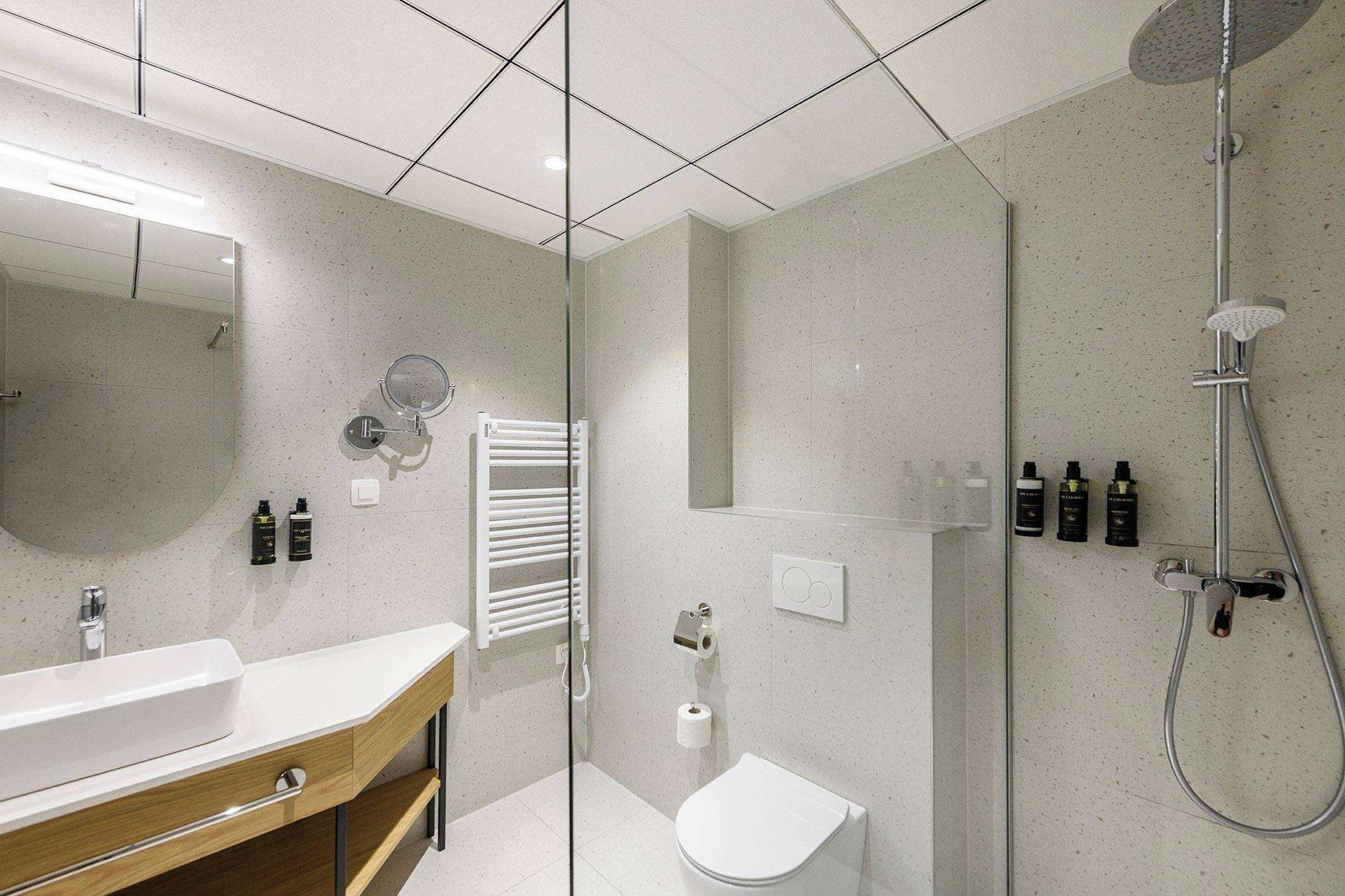 Un bagno moderno con cabina doccia in vetro, lavandino bianco e water.