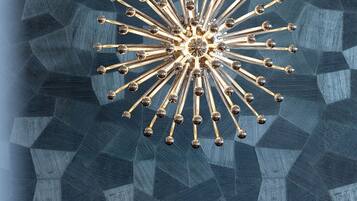 Ein Raum mit Wand in geometrischem Muster und einem zentralen Kronleuchter.