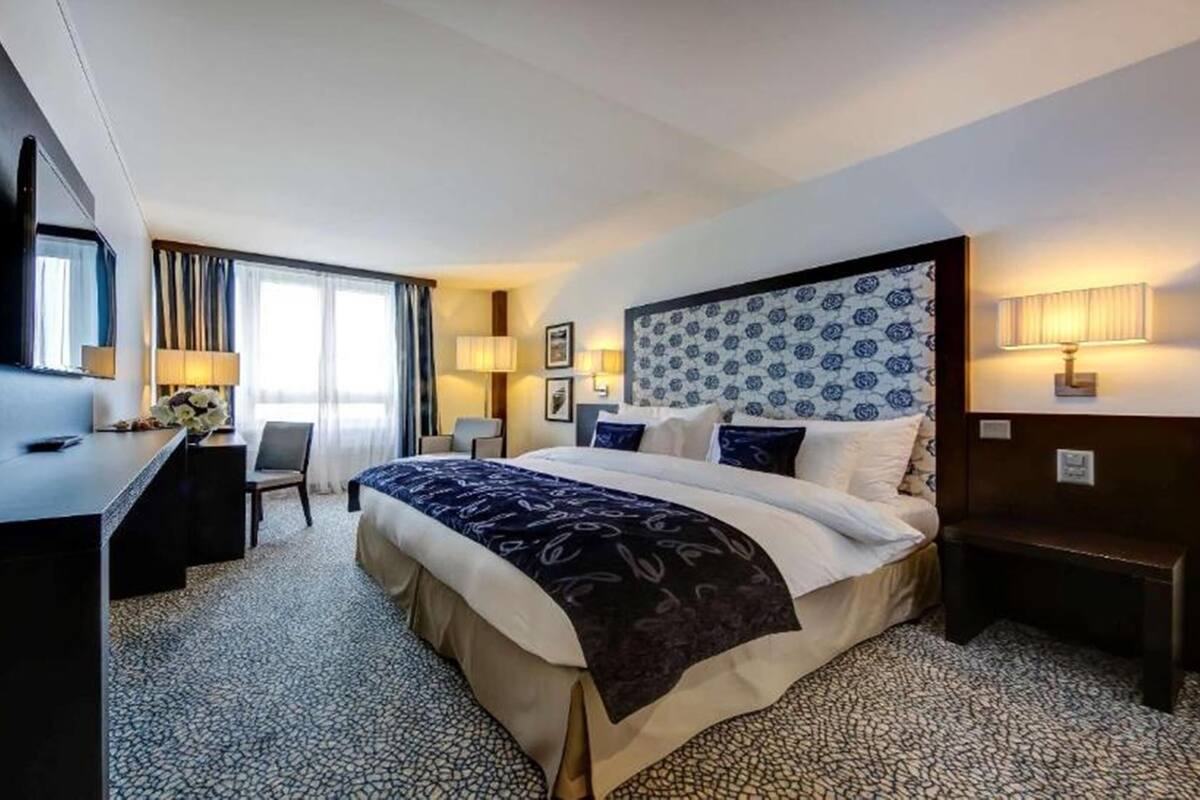 A hotel room with a large bed, a desk, a chair, and a TV.
