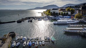 A marina with boats docked, a waterfront promenade, and buildings in the background.