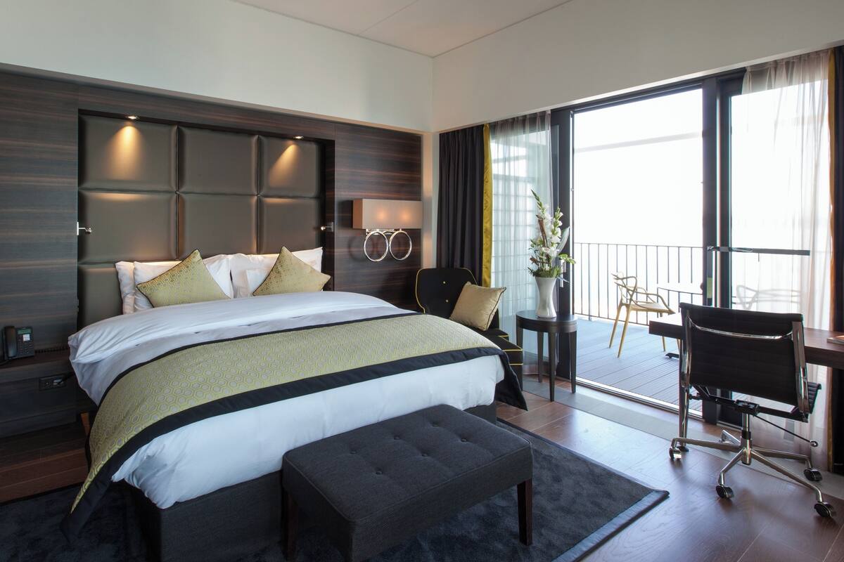 A modern hotel room with a large bed, a desk, and a chair.