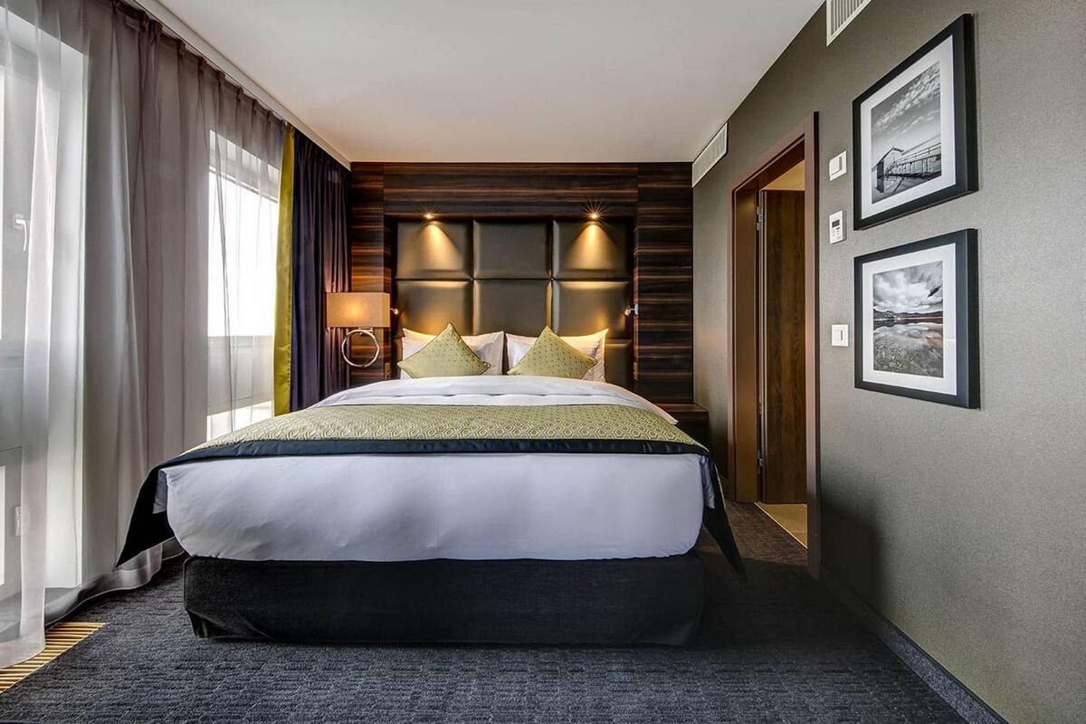 A hotel room with a large bed, a bedside lamp, and framed pictures on the wall.