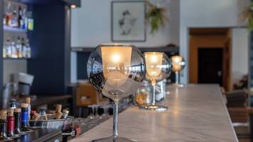 A bar area with wine glasses and bottles on the counter.