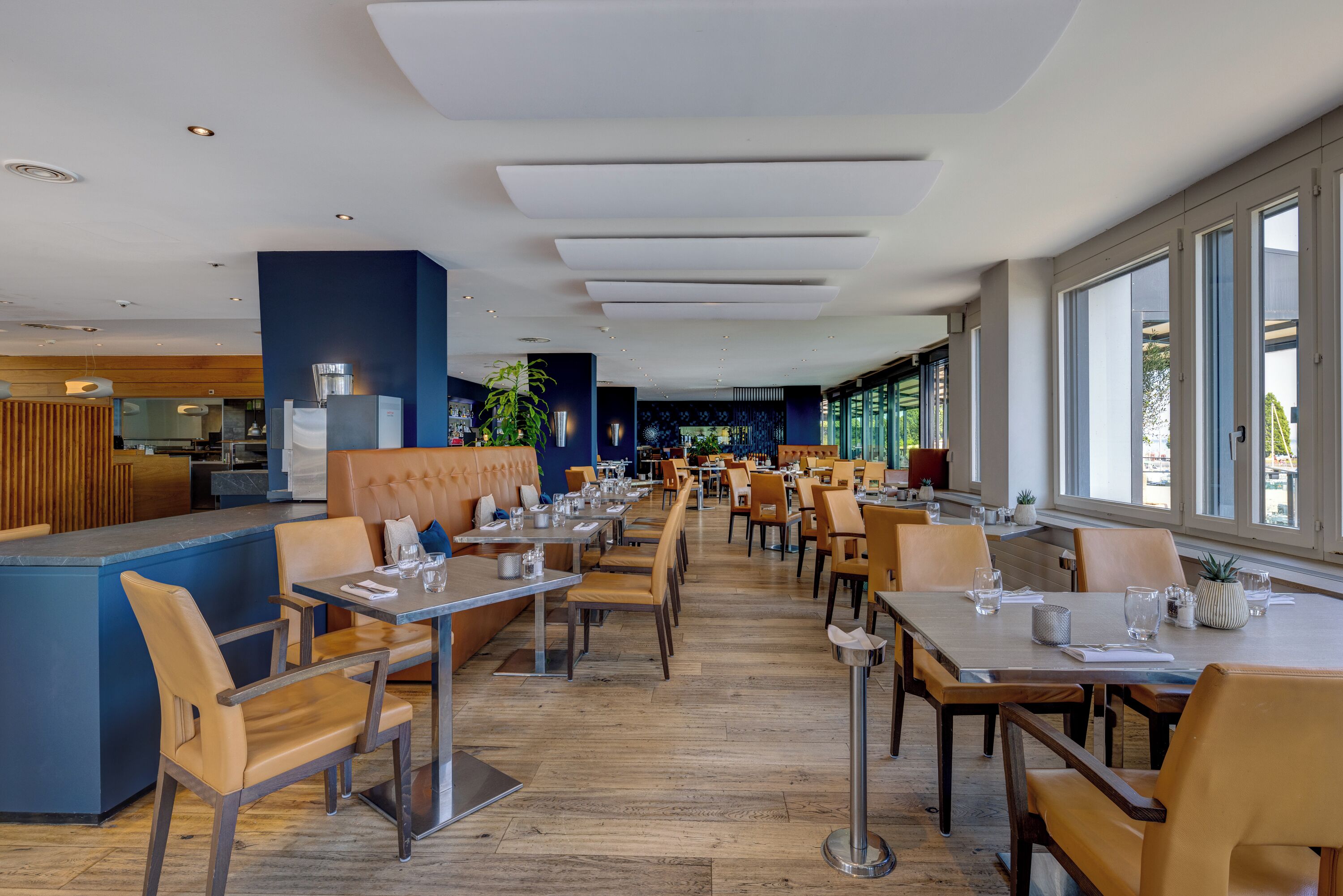 Un restaurante espacioso con techos altos, iluminación moderna y grandes ventanales que ofrecen vistas al exterior.