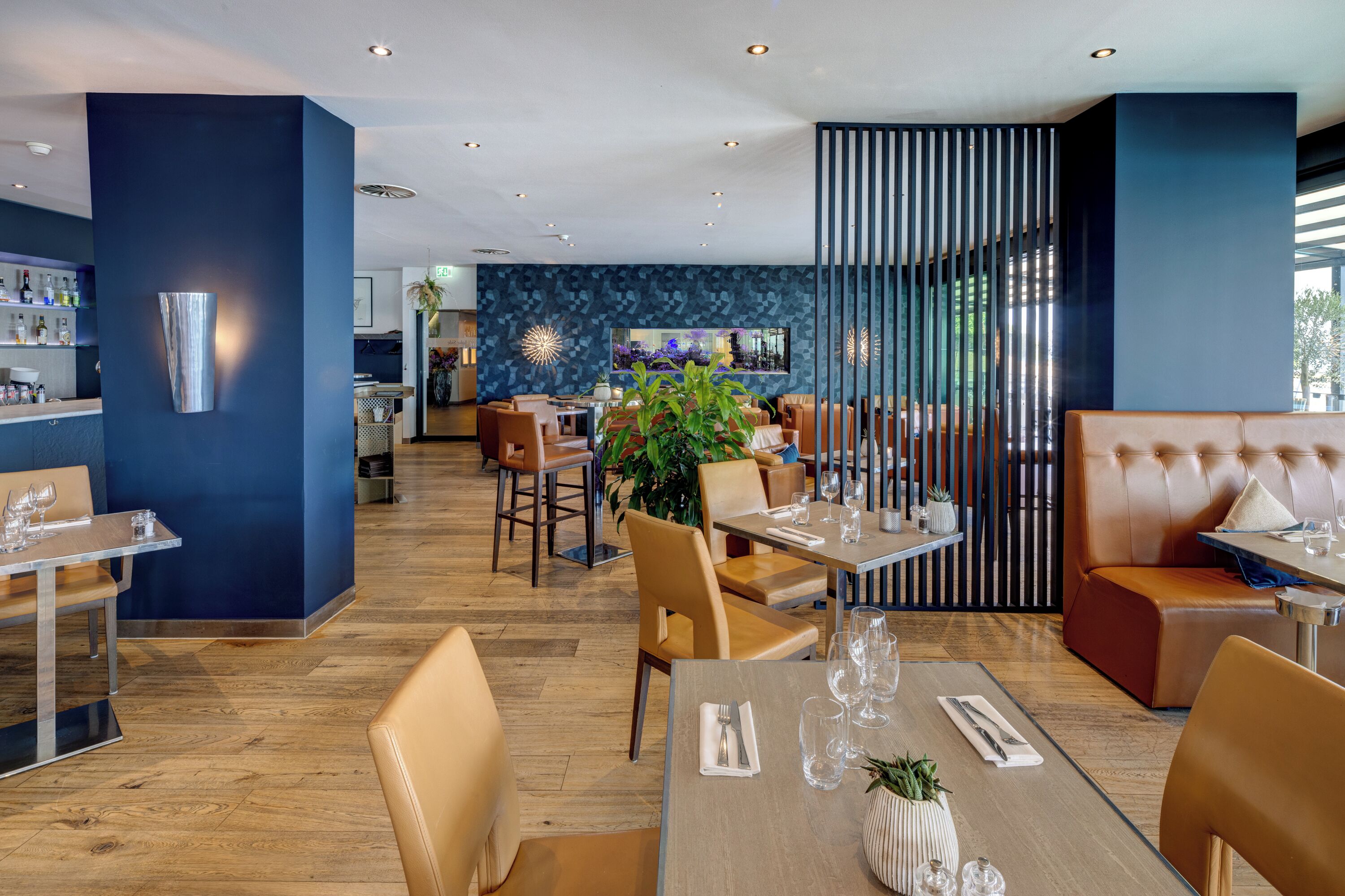 En modern restaurang med en bardel, trägolv och en variation av sittplatser, inklusive avskilda bås och bord.