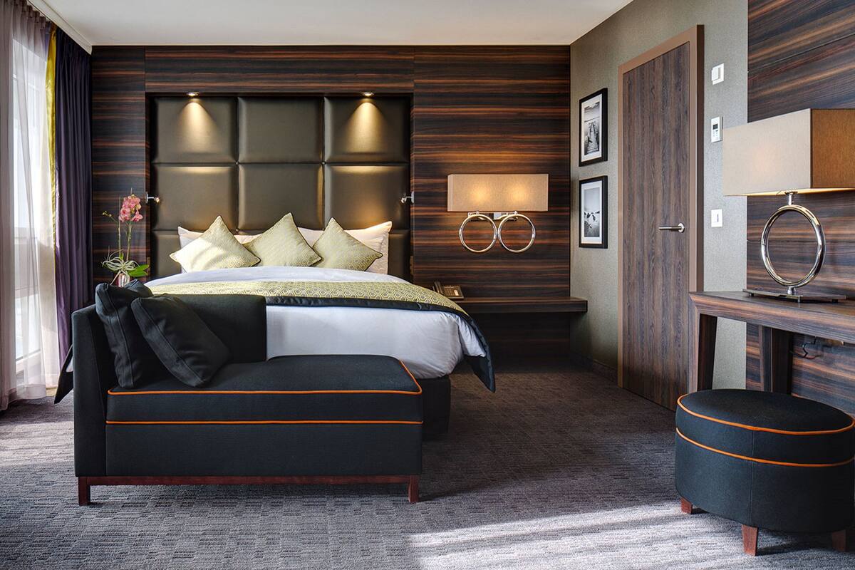 A modern hotel room with a large bed, a desk, and a seating area.