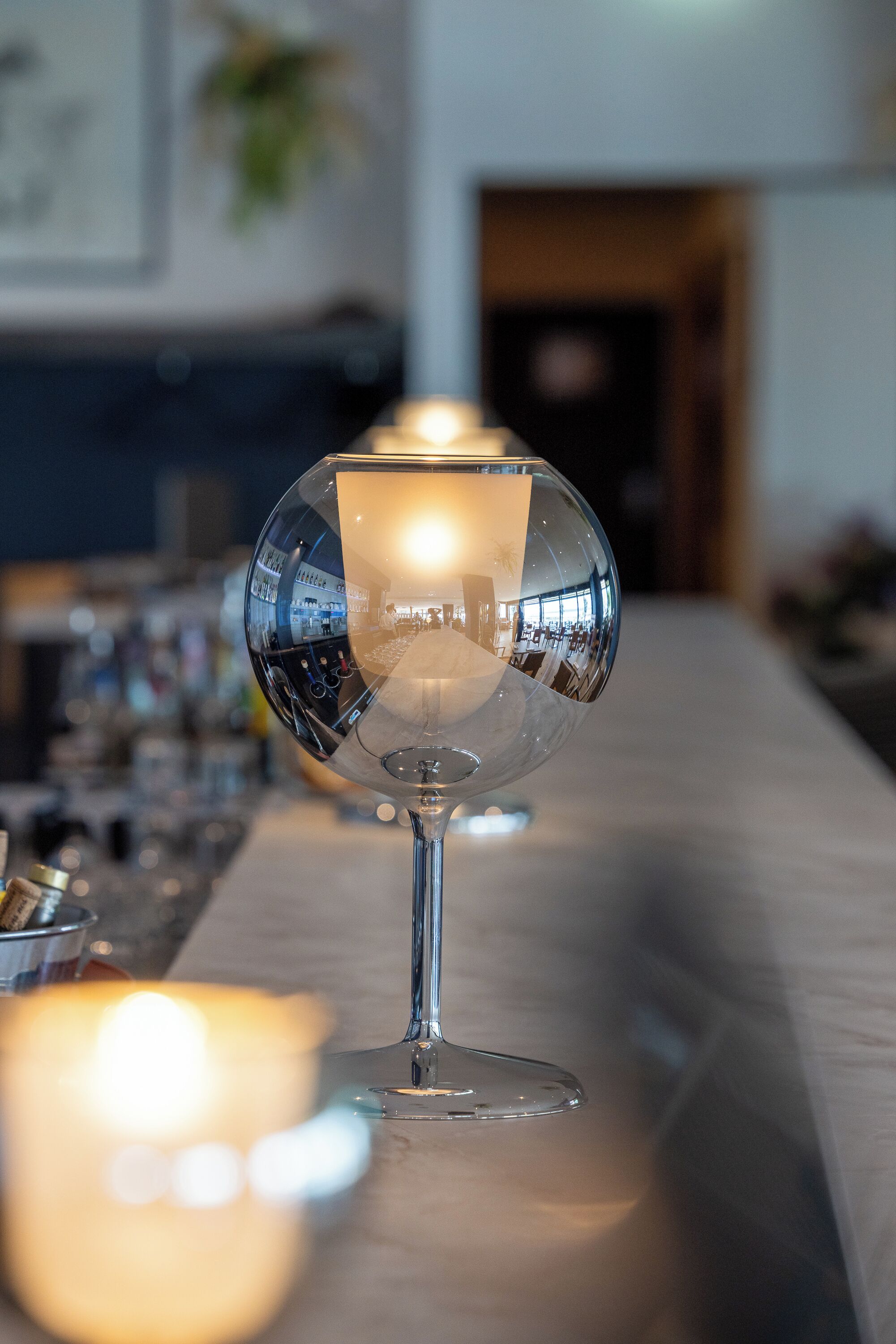 A bar area with a reflective glass table and a candle.