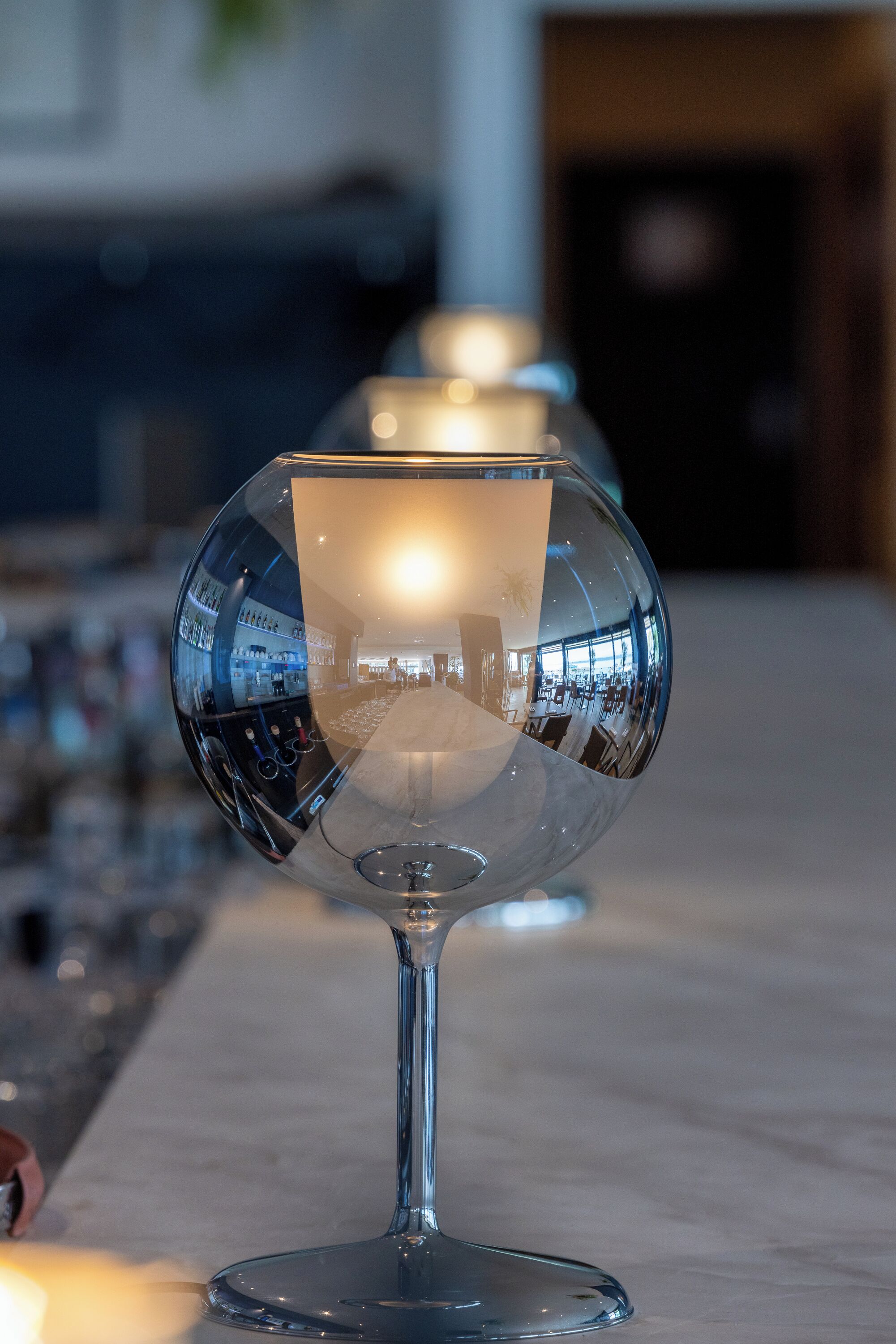 A clear glass dome with a reflective interior, placed on a marble surface.