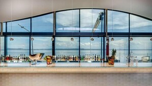A bar with a curved glass wall, a variety of bottles, and a pineapple centerpiece.