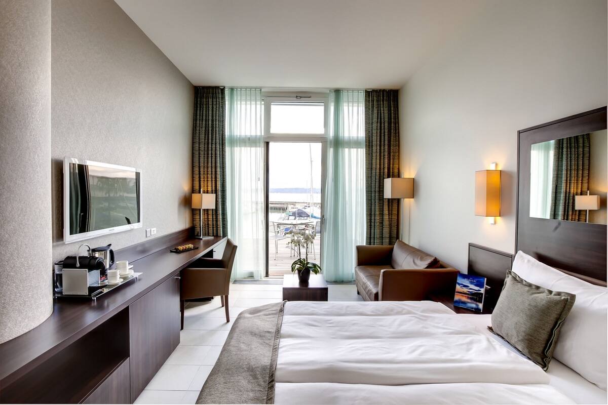 A hotel room with a bed, desk, chair, and a TV.