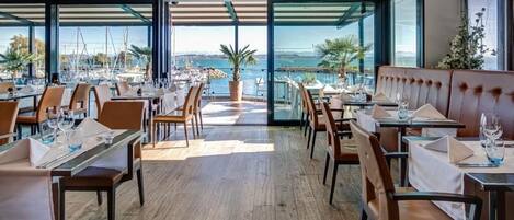 Un restaurante con vistas al mar, suelo de madera y mobiliario moderno.
