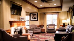 A spacious living room with a fireplace, multiple seating options, and a large window with curtains.